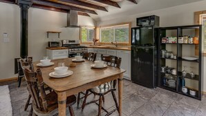 Una cocina con una mesa de madera preparada para comer, un refrigerador y un microondas.