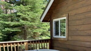 Un jacuzzi en una terraza de madera, con una cabaña de madera al fondo.