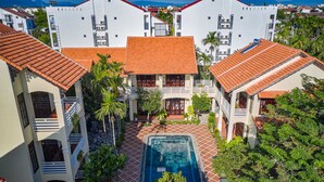 Une cour avec une piscine, entourée de bâtiments aux toits recouverts de tuiles rouges et dotés de balcons.