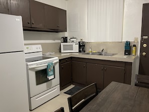 A compact kitchen with a refrigerator, stove, microwave, and a coffee maker. - Incredible Location! (Sinajana)