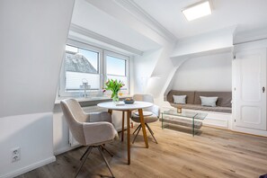 A modern loft apartment with a dining area, a sofa, and a view of the outside.