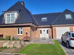 A two-story house with a brick facade, a sloped roof, and a garage. - Holiday Apartment Haus Westsee OG Frisian Style Near the Beach (Wenningstedt)