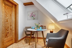 A room with a skylight, wooden door, dining table with chairs, and a lamp. - Holiday Apartment Haus Westsee OG Frisian Style Near the Beach (Wenningstedt)