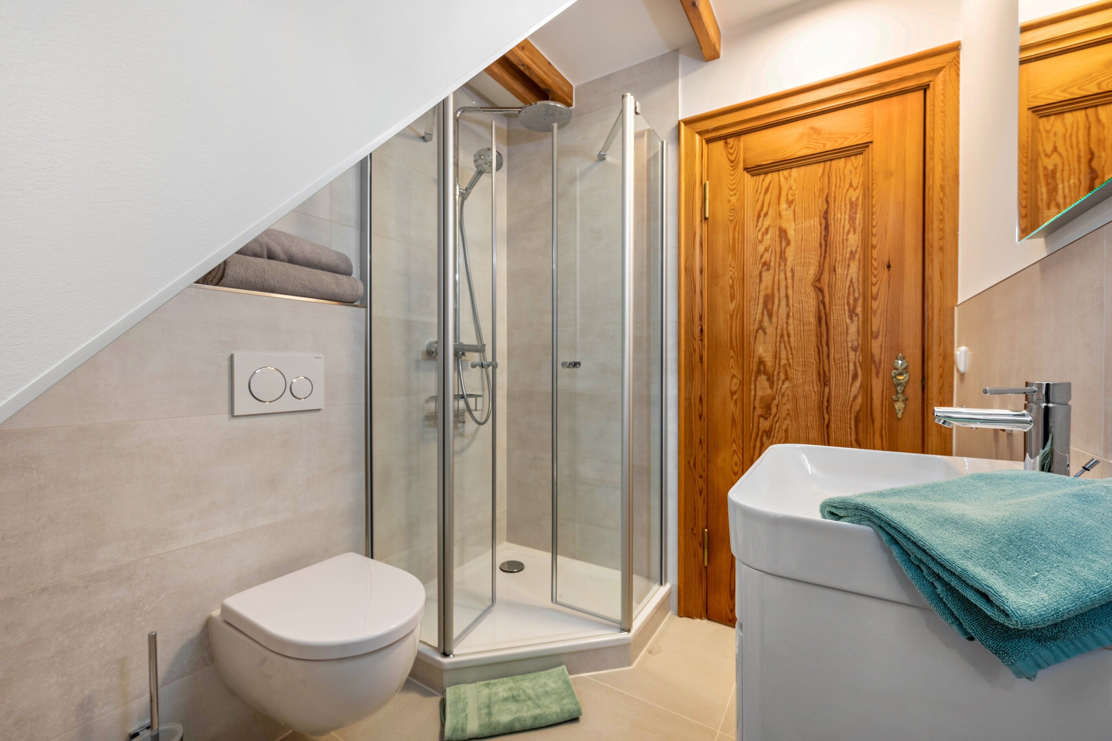 A modern bathroom with a glass-enclosed shower, a white toilet, and a sink with a towel.