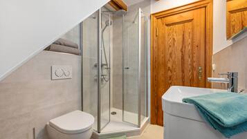 A modern bathroom with a glass-enclosed shower, a white toilet, and a sink with a towel.
