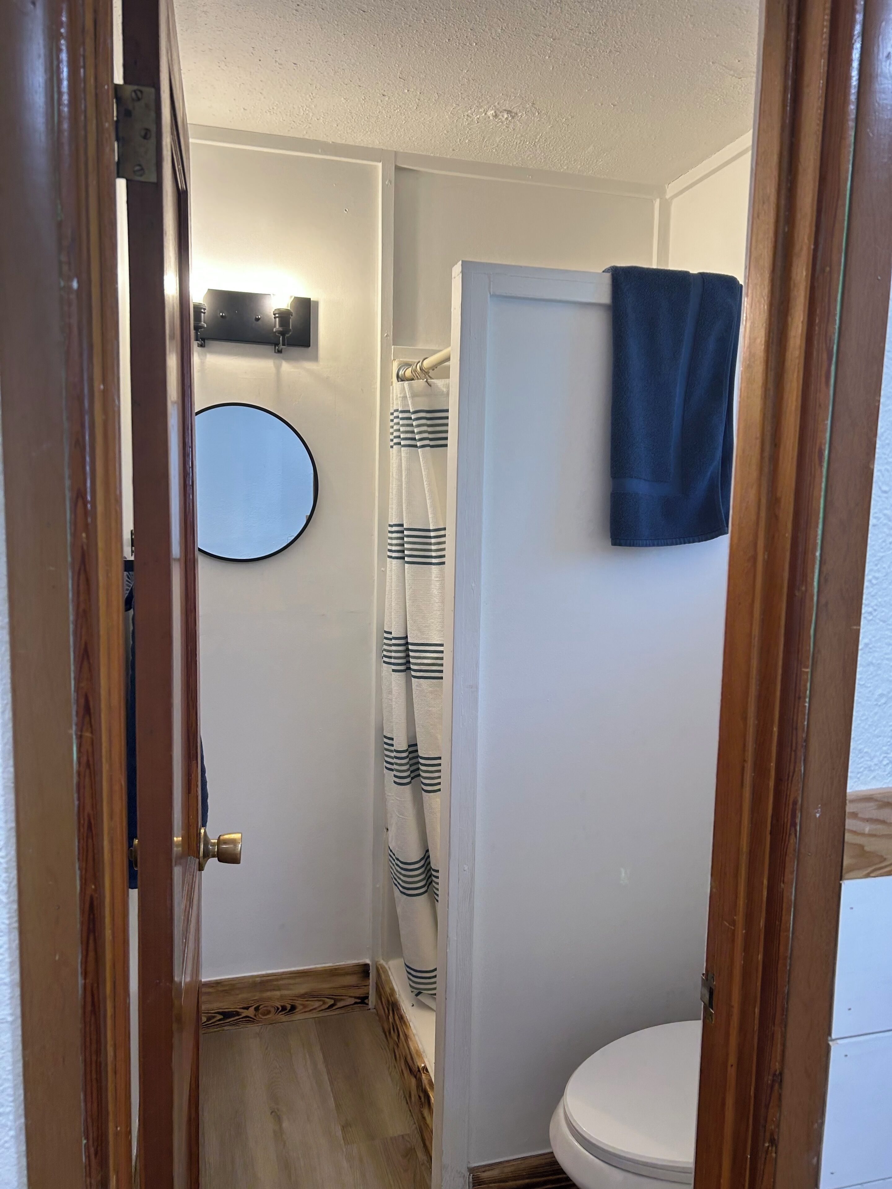 Ein Badezimmer mit Toilette, einer Duschvorhang, einem Handtuch an der Wand und einem Spiegel.