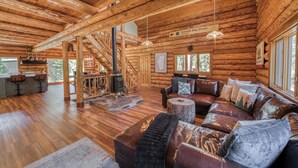 A log cabin interior with a wooden staircase, a fireplace, a leather sofa, and a dining area. - Tahoe Wanderer - Super Cool Luxury Log Cabin with NEW Kitchen, Private Hot Tub (Tahoe Vista)