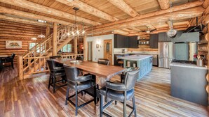 A spacious wooden cabin with a large dining table, bar stools, a kitchen area, and a staircase leading to a loft. - Tahoe Wanderer - Super Cool Luxury Log Cabin with NEW Kitchen, Private Hot Tub (Tahoe Vista)