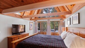 A bedroom with a large bed, a TV, wooden furniture, and a view through a window. - Snowy Paws Alpine Meadows - Ski Shuttle- Dog OK - Close to Slopes - Amazing Views (Olympic Valley)