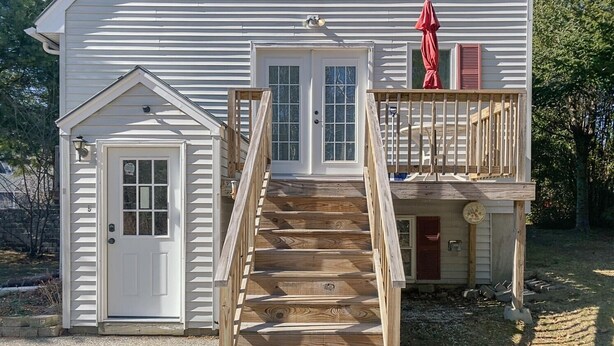 Una casa de dos pisos con una escalera de madera que lleva a un balcón.