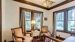 A room with a wooden chair, a table, a lamp, and a rug.