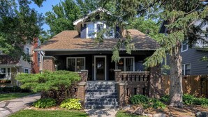 A two-story house with a front porch, a brick entrance, and a well-maintained lawn.