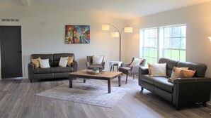 A modern living room with a dark leather sofa, a wooden coffee table, and a colorful abstract painting on the wall. - Edward House, on 7 acres, not far from Notre Dame & Golf Course (Walkerton)