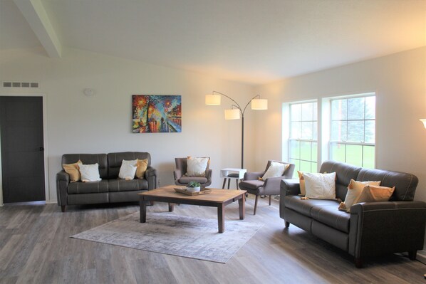 A modern living room with a dark leather sofa, a wooden coffee table, and a colorful abstract painting on the wall.