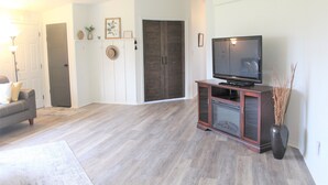 A living room with a flat-screen TV on a wooden cabinet, a grey sofa, and a large mirror on the wall. - Edward House, on 7 acres, not far from Notre Dame & Golf Course (Walkerton)