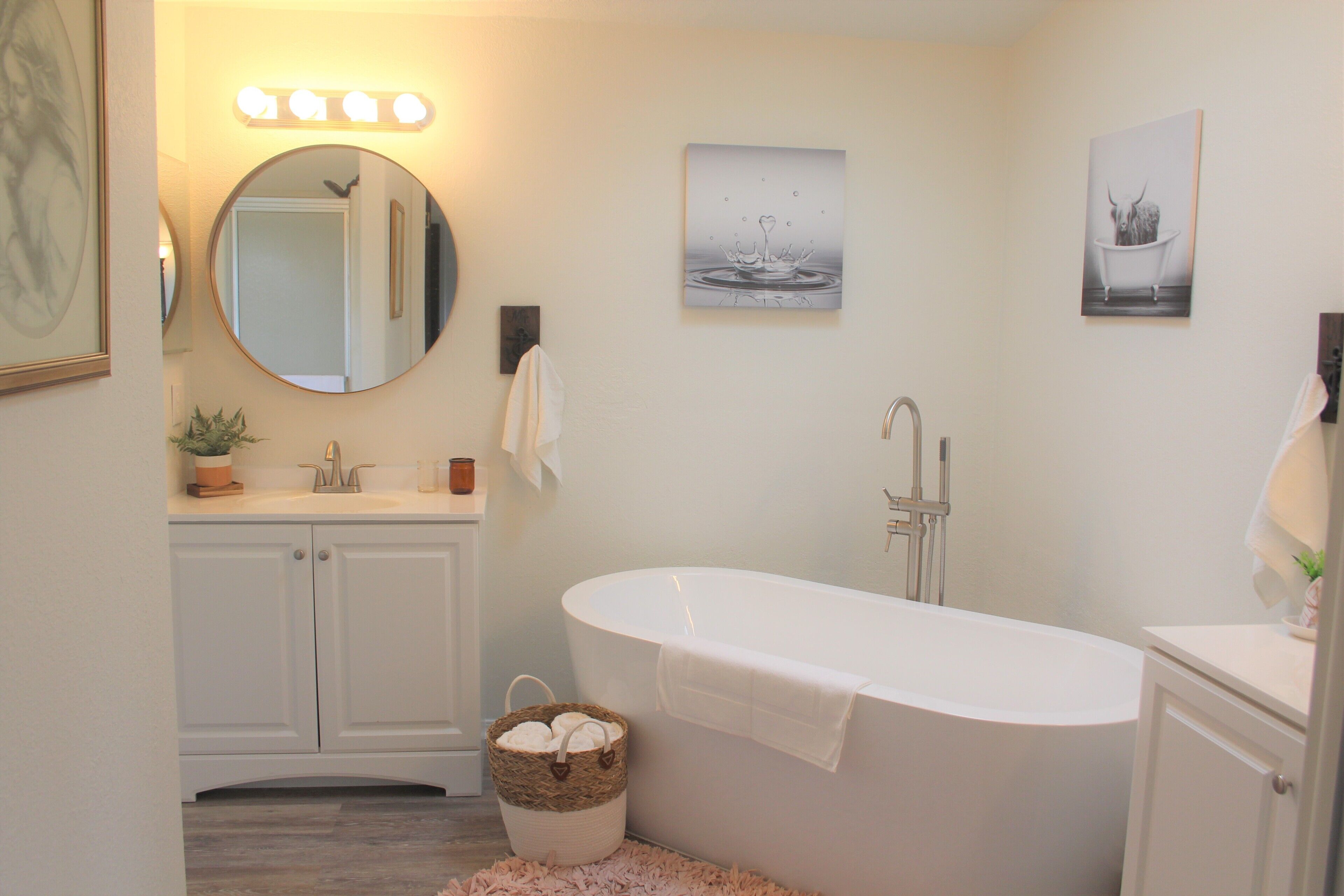 Ein Badezimmer mit einer weißen Badewanne, einem Waschbecken, einem Spiegel und Wandleuchten.