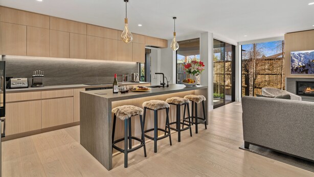 A modern kitchen with a central island, bar stools, and a seating area with a sofa and fireplace. - Central Queenstown Villa & Spa (Queenstown)