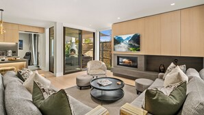 A modern living room with a fireplace, comfortable seating, and a view of the outdoors. - Central Queenstown Villa & Spa (Queenstown)