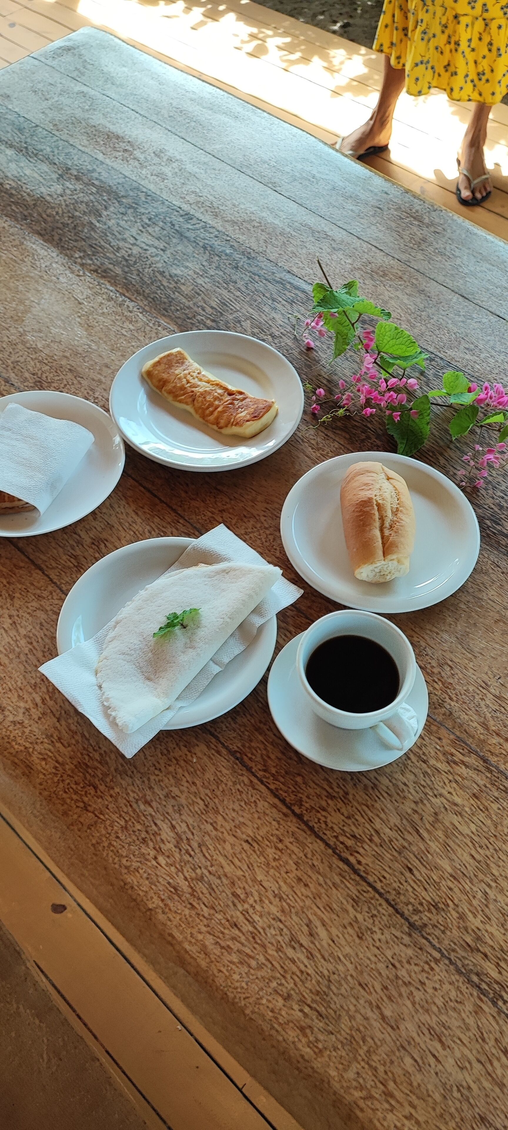 A wooden table with a croissant, a pastry, a cup of coffee, and a napkin.