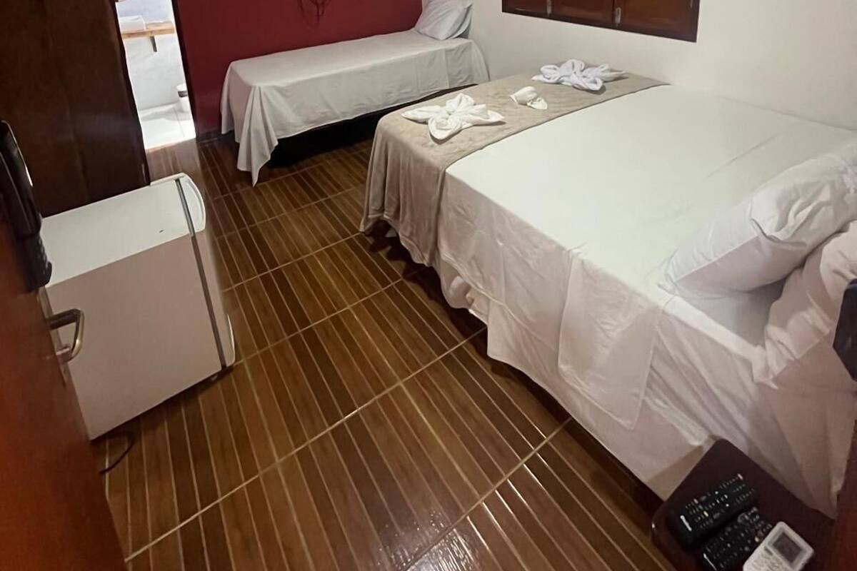 A hotel room with two beds, a TV, a wardrobe, and a refrigerator.