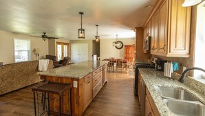 A spacious kitchen with wooden cabinets, granite countertops, and a central island. - 4BR/3BA on a Golf Course close to Beach, Casinos & Downtown Ocean Springs! (Ocean Springs)