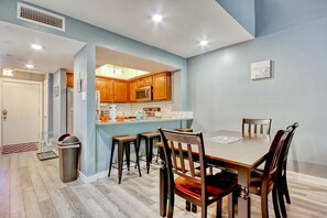 Enjoy family meals in this spacious kitchen and dining area, featuring a wooden table and matching chairs.