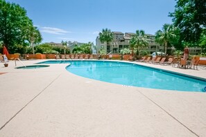 Relax by the resort's clear blue pool surrounded by lounge chairs and umbrellas, with comfortable accommodations nearby.
