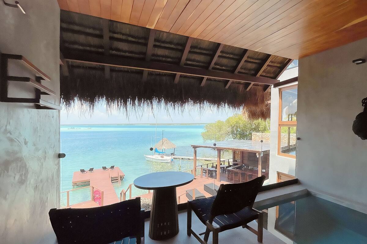Un balcón con vistas al mar, una mesa y sillas.