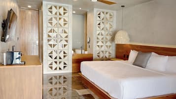 Una habitación de hotel moderna con una cama grande, cabecera de madera y un panel decorativo blanco.