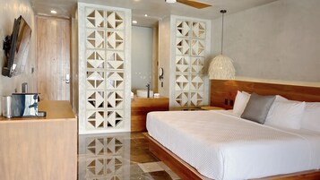 Una habitación de hotel moderna con una cama grande, cabecera de madera y un panel decorativo blanco.