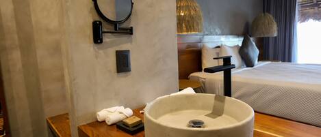 A modern bathroom with a round sink, a mirror, and a wooden vanity.
