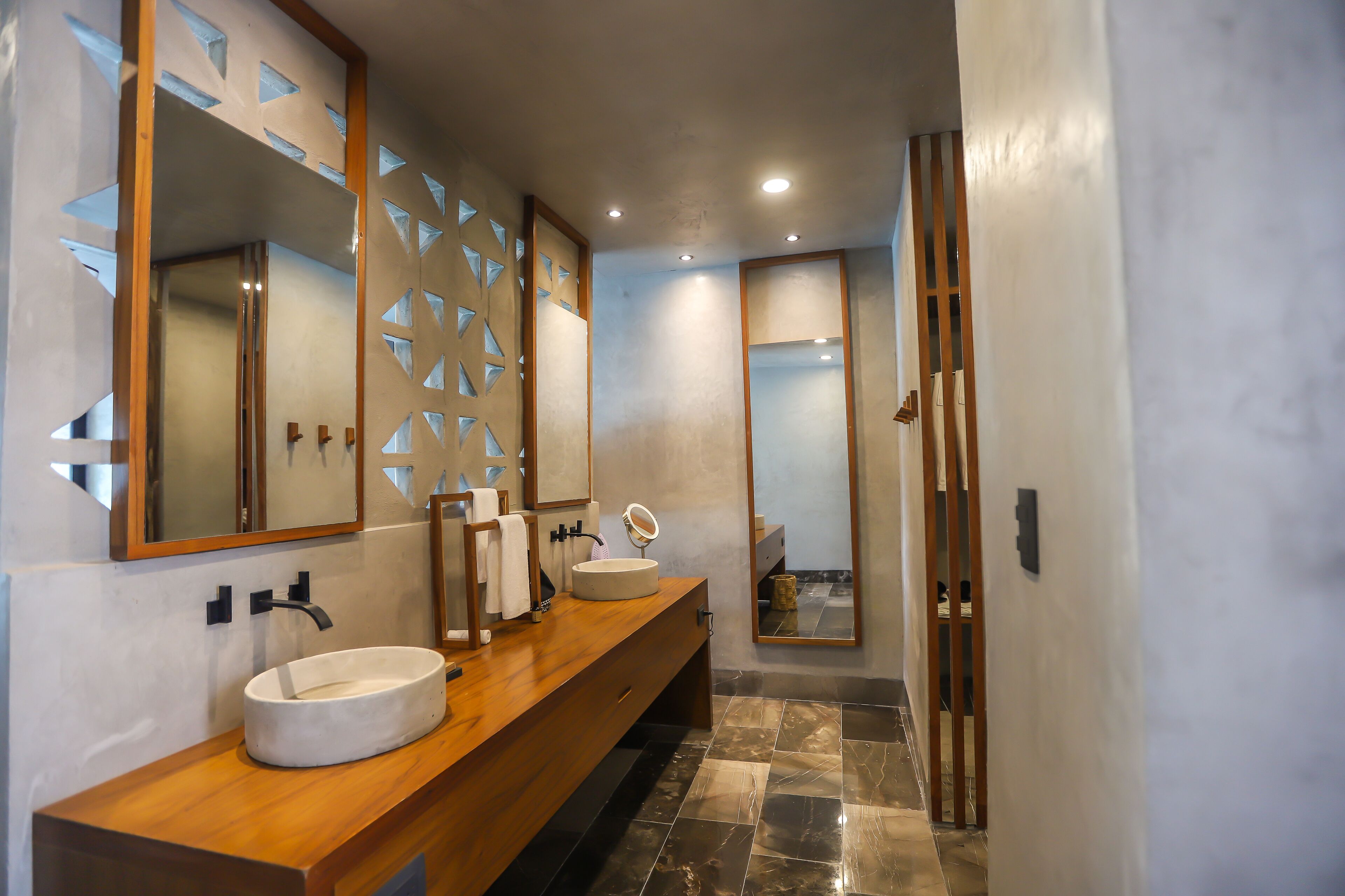 A modern bathroom with a wooden vanity, a round sink, and a large mirror.