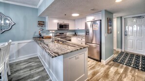 A modern kitchen with white cabinets, stainless steel appliances, and a granite countertop.