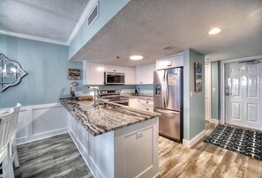 Enjoy cooking in this well-equipped kitchen with a central island, refrigerator, and microwave.