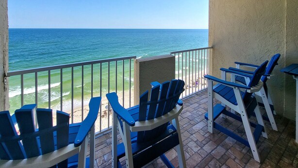 A balcony with blue chairs and a view of the ocean.