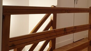 Una escalera de madera con tragaluces y una puerta blanca al fondo.