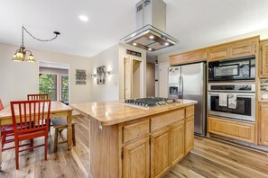 A kitchen with wooden cabinets, a central island, a stove, a refrigerator, and a microwave.
