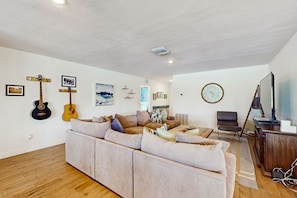 Relax in this stylish living room with a sofa, coffee table, and TV on a cabinet, plus guitars and a clock on the wall.
