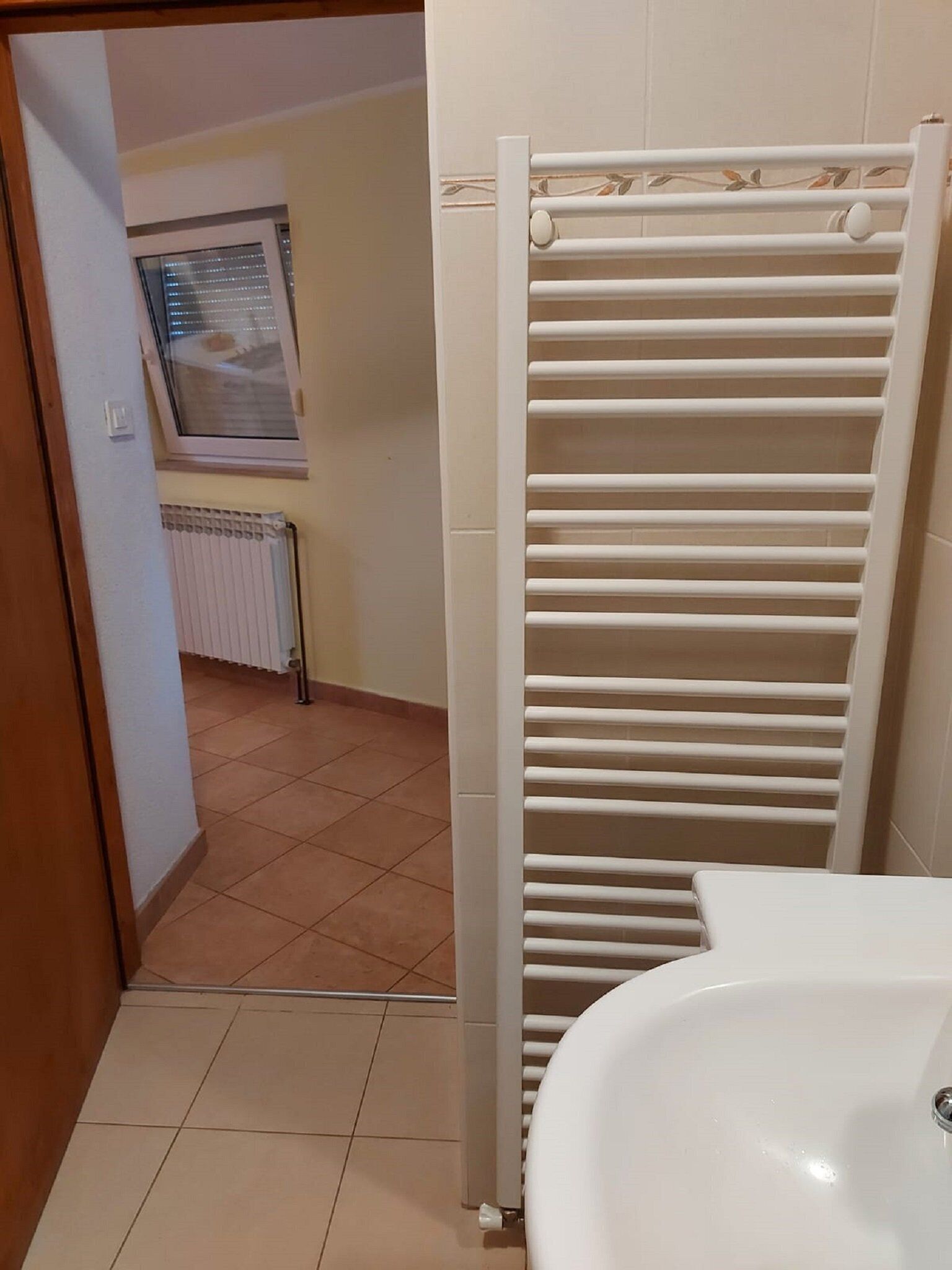 A bathroom with a white sink, a towel rack, and a radiator in the background.