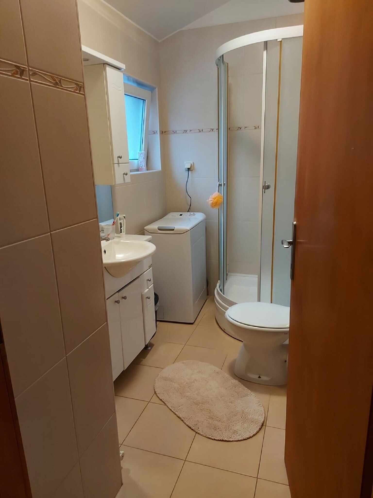 A compact bathroom with a toilet, sink, and shower.