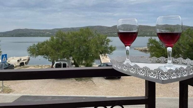 Dos copas de vino sobre una mesa, con vistas a un lago y montañas al fondo.