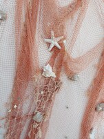 Un gros plan d’un filet avec des étoiles de mer et des coquillages.