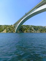 Un puente sobre un cuerpo de agua, con terreno rocoso y vegetación escasa al fondo.