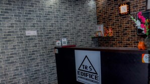 Un comptoir d’accueil avec une pancarte indiquant : « TRS EDIFICE, LA MAISON D’HÔTES DE LUXE ».