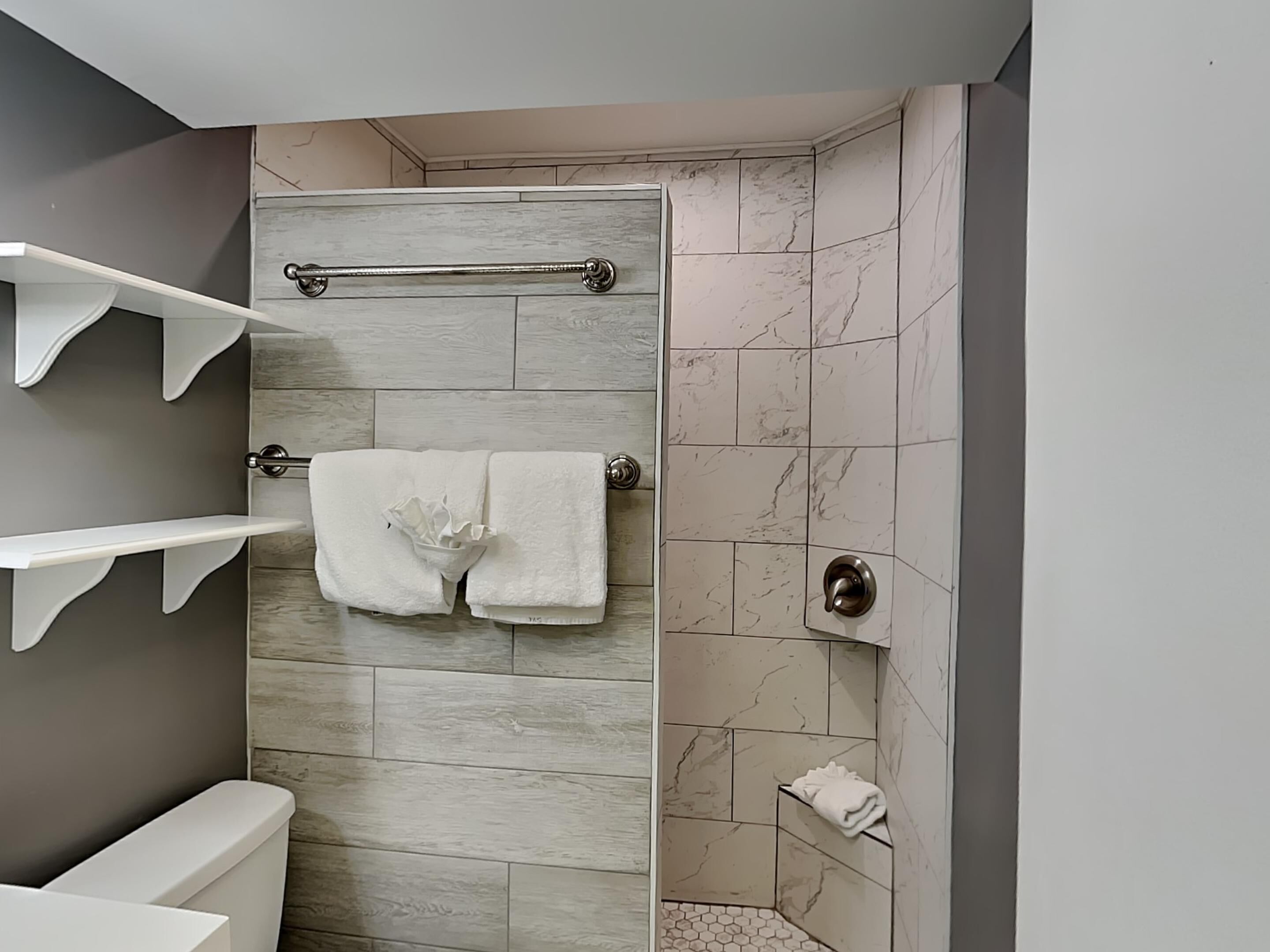 Un baño moderno con ducha, inodoro y toalleros.