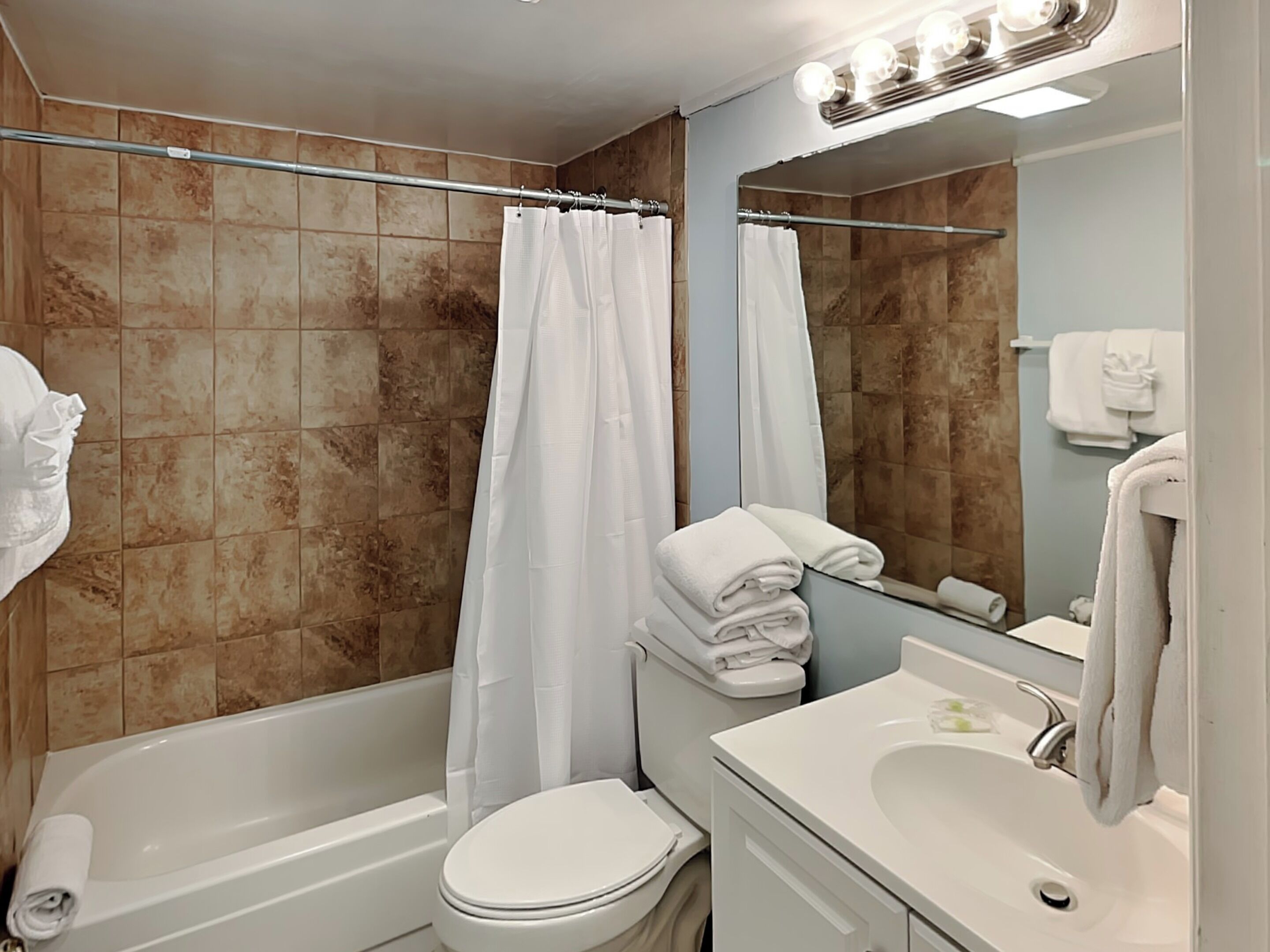 Une salle de bain avec une baignoire, des toilettes et un lavabo, le tout de couleur blanche.