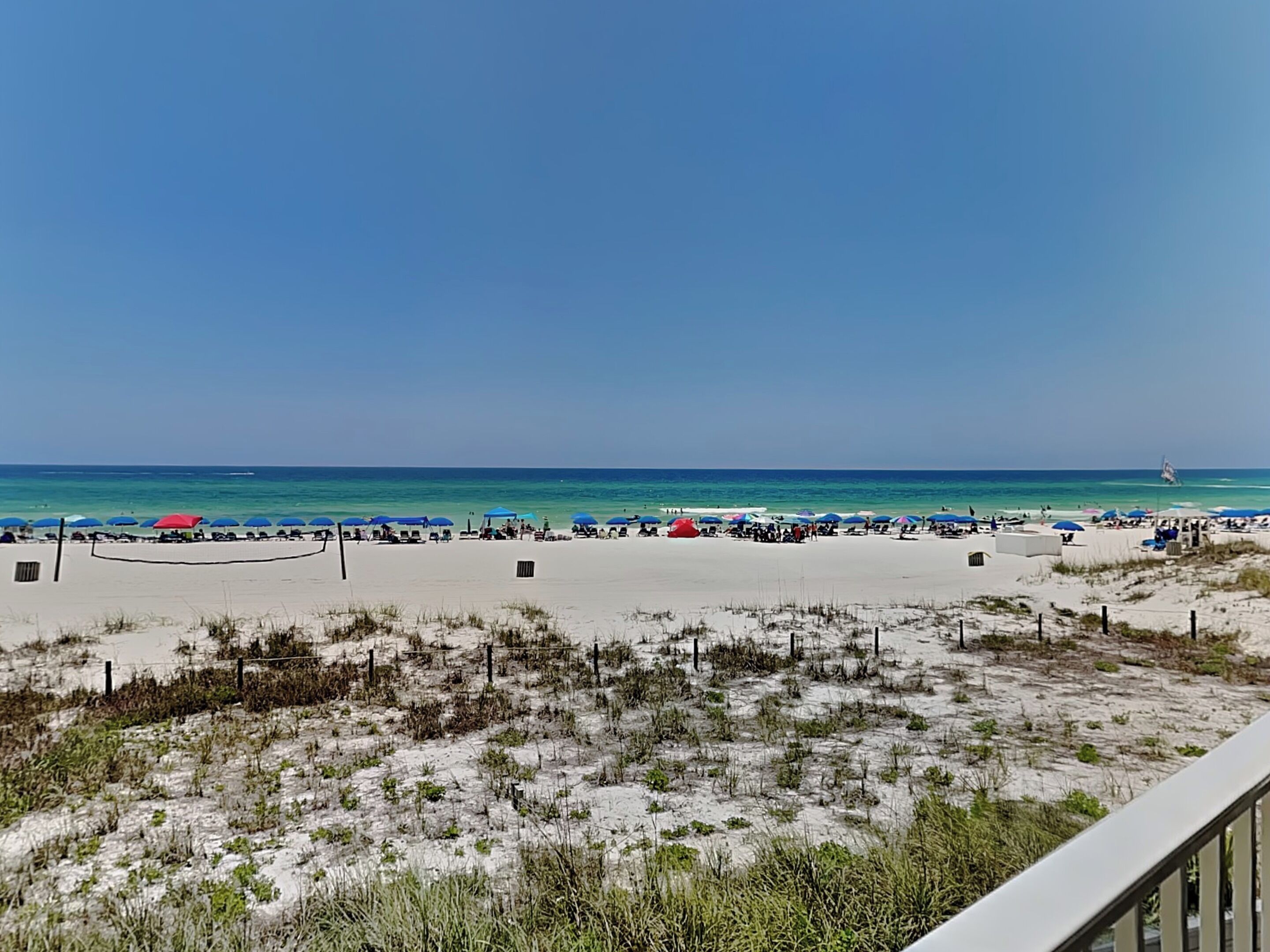 A beach with a clear sky, a sandy shore, and a few umbrellas.