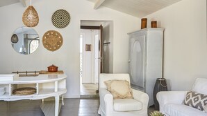 Un salon moderne avec un canapé blanc, un fauteuil blanc, un meuble blanc et un coin repas comprenant une table blanche et des étagères.