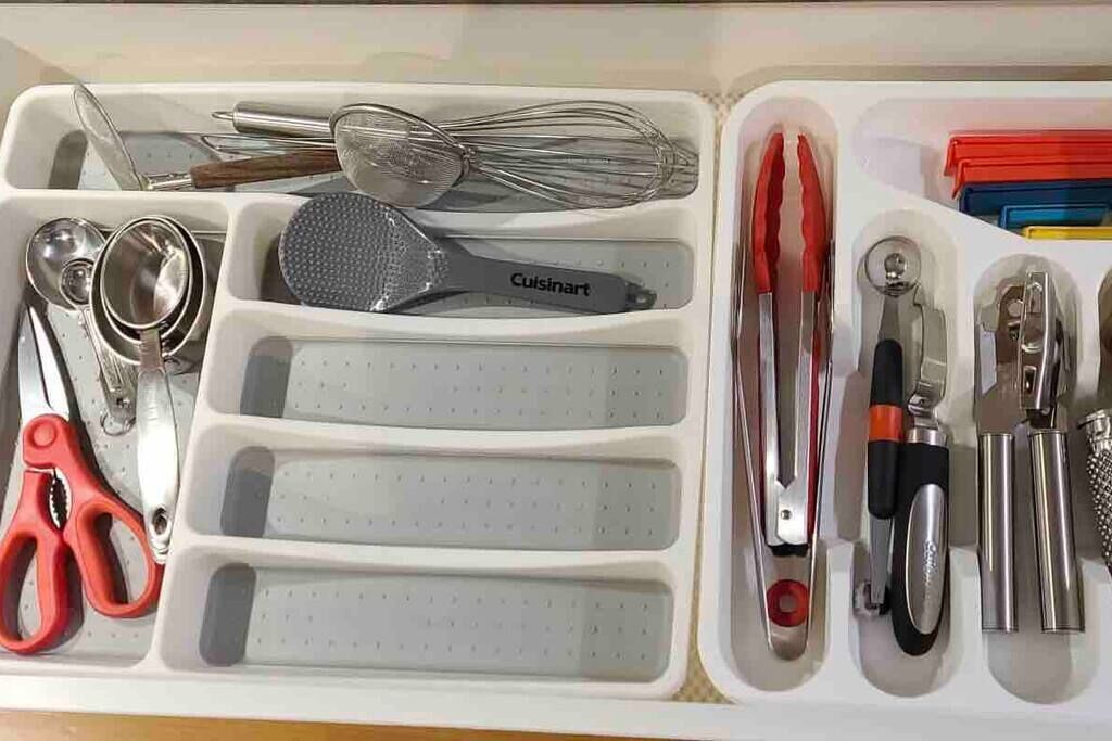 A kitchen utensil organizer with compartments for various tools like whisks, tongs, and a grater.