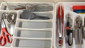 A kitchen utensil organizer with compartments for various tools like whisks, tongs, and a grater.